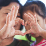 Asian grandmother and little child girl making heart shape with hands together with love